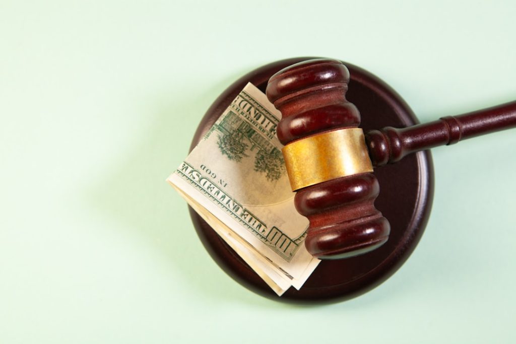 Wooden judge gavel and money in a bowl on green background